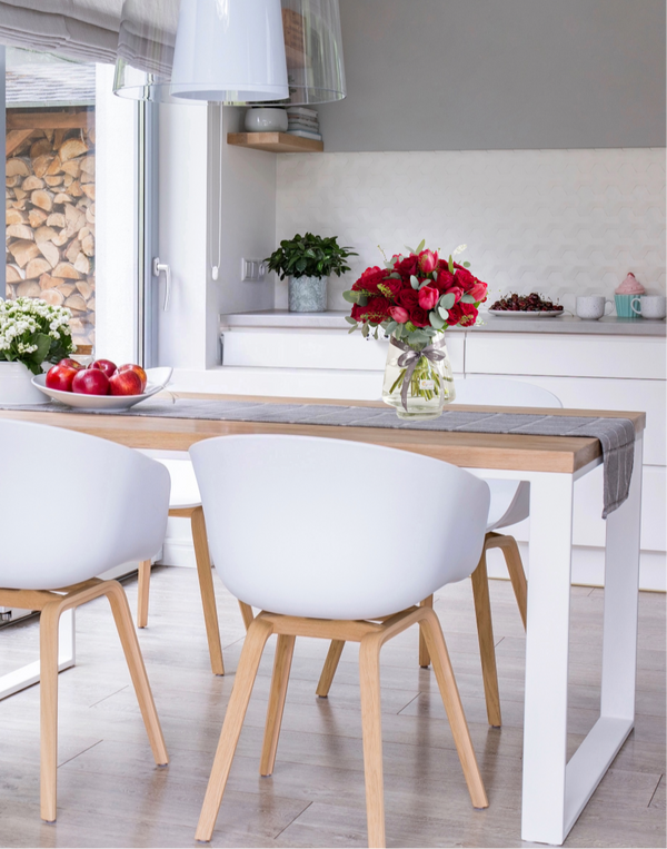 Elegant red roses in a glass vase placed on a modern dining table. A timeless floral arrangement perfect for romantic gifts, home decor, and special celebrations.