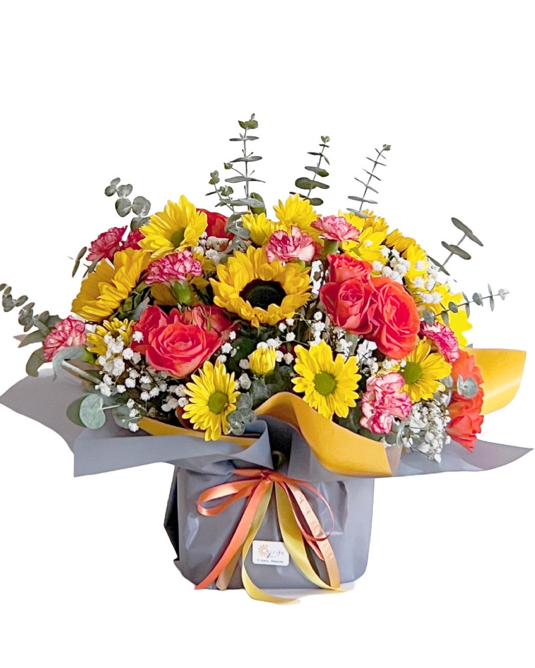 Sunshine Bliss floral arrangement with golden sunflowers, white daisies, pink spray roses & lush greenery in an elegant vase.