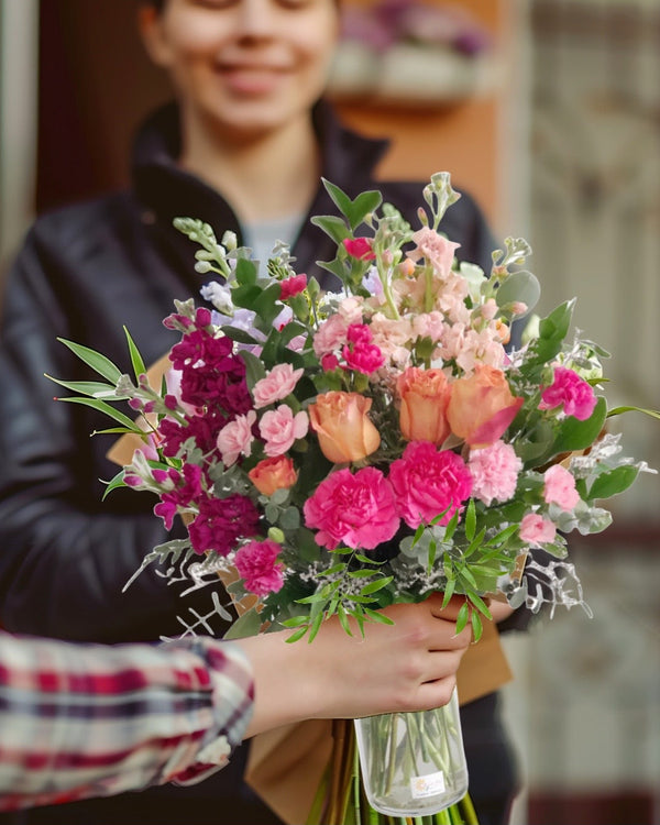 Heaven Palette floral arrangement featuring a mix of colorful roses, spray roses, stock flowers, carnations, eucalyptus, and greens, elegantly presented in a glass vase.